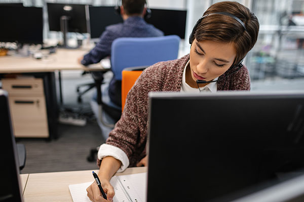Worker with headset writing something down
