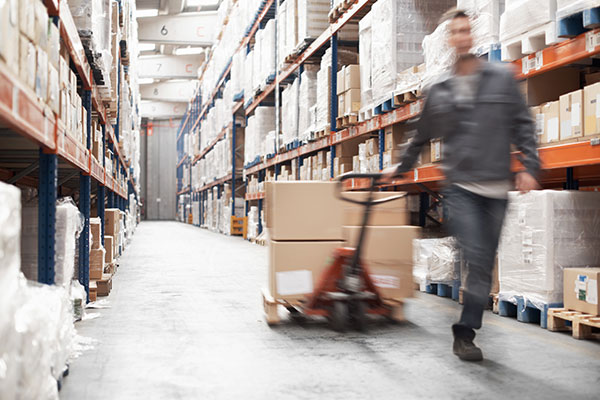 Worker drags cart through warehouse