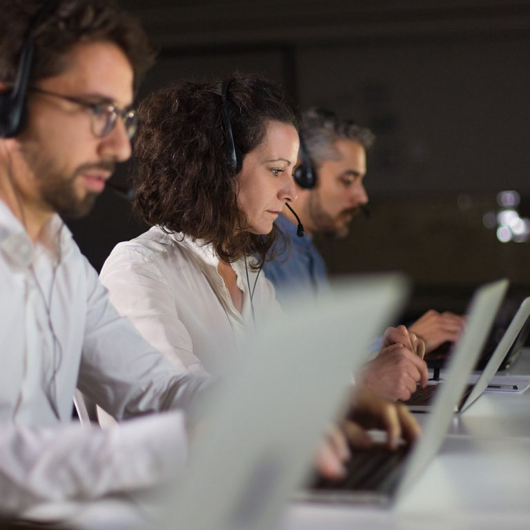 Workers with headsets on laptops