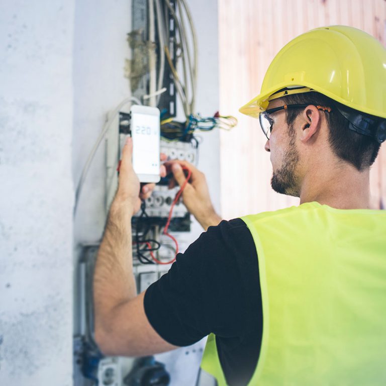Worker in hard hat and hi-vis fixing wiring