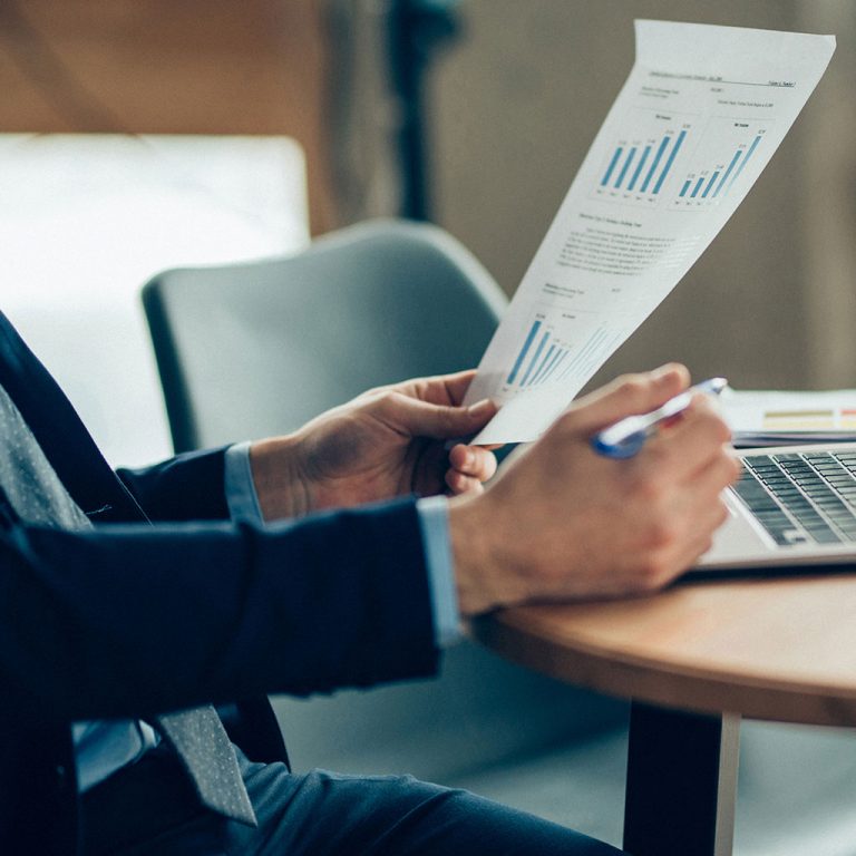 Worker with data on paper and laptop